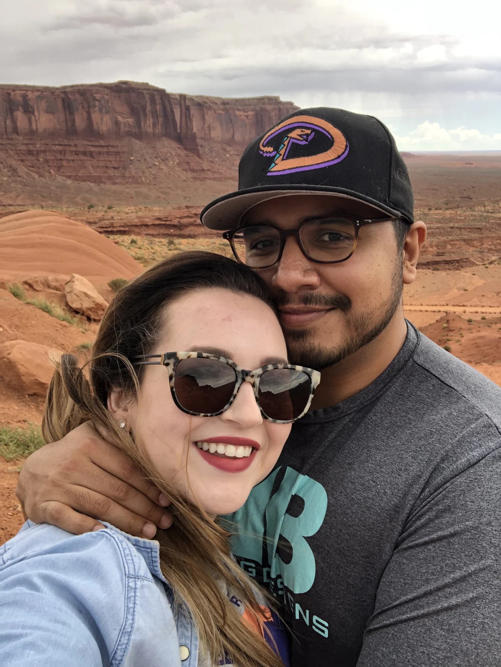 Elena and Vincent smiling together with red desert mesas behind them