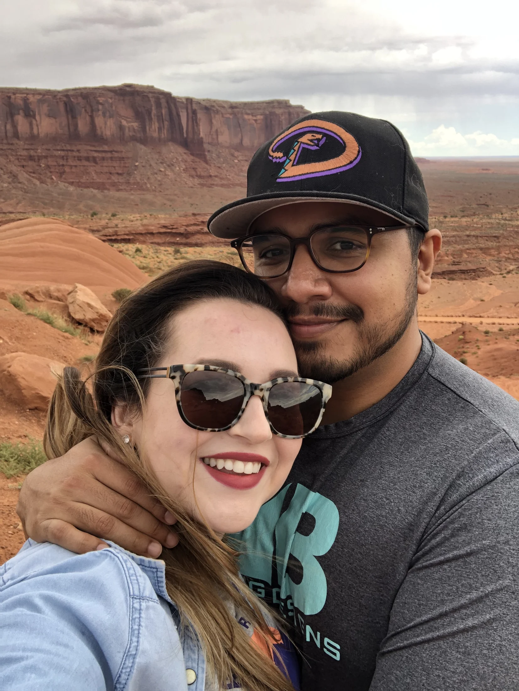 Elena and Vincent smiling together with red desert mesas behind them